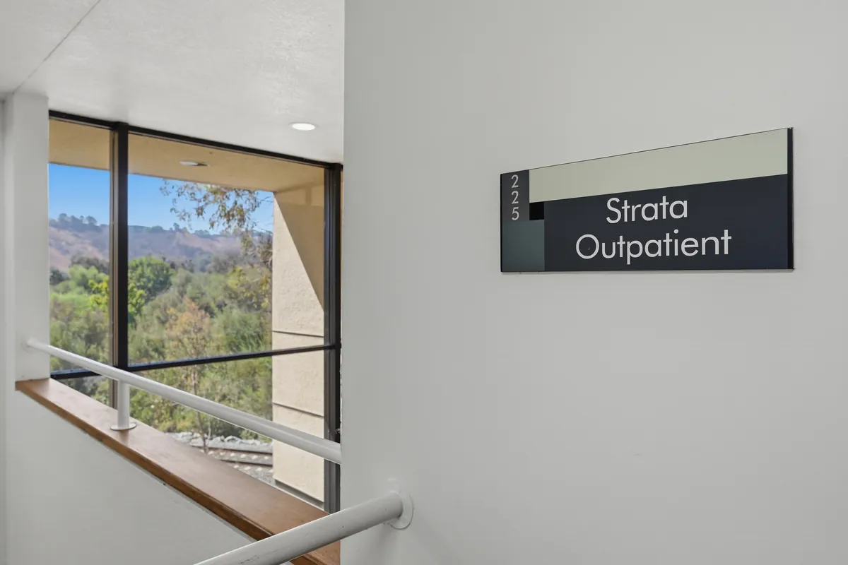 A wall-mounted sign reading Strata Outpatient beside a window looking out to the canyon